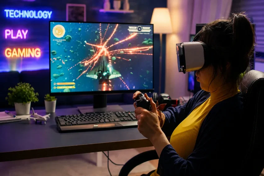 Person wearing a VR headset playing a space game with controller at a modern gaming setup, with “Technology Play Gaming” neon text in the background.